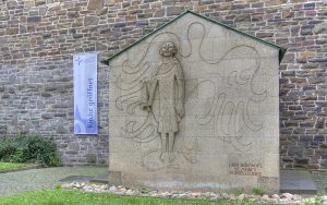 Lukaskirche: Eingang mit Relief "Lukas" und Transparent "Kirche geöffnet"